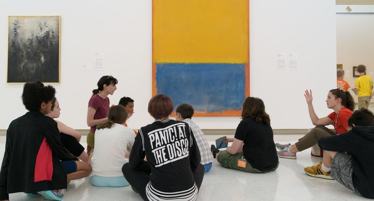 Campers discuss art in the galleries while sitting in front of a Mark Rothko painting.