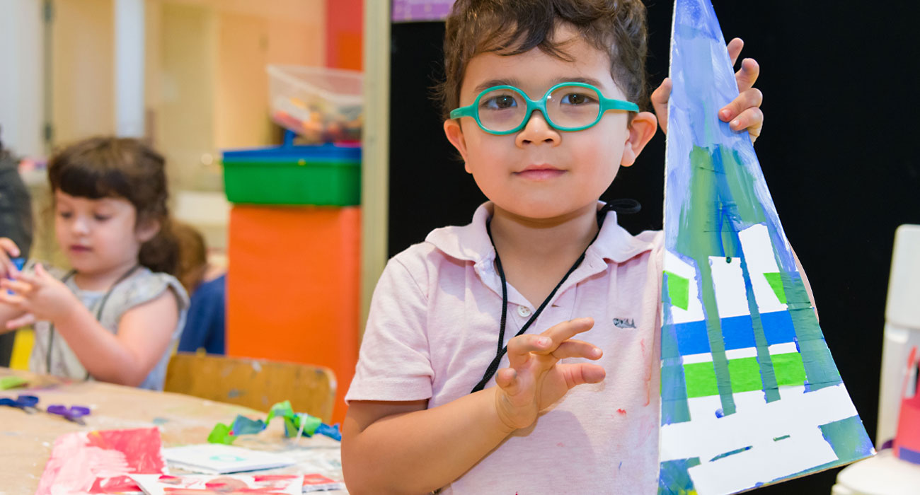 A boy displays his paper tree.