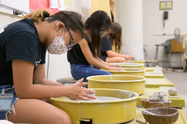 Young artists spin clay on a wheel.