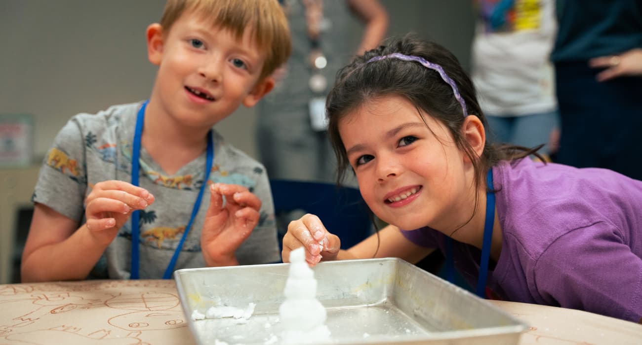 children looking at a small snowman on a platter