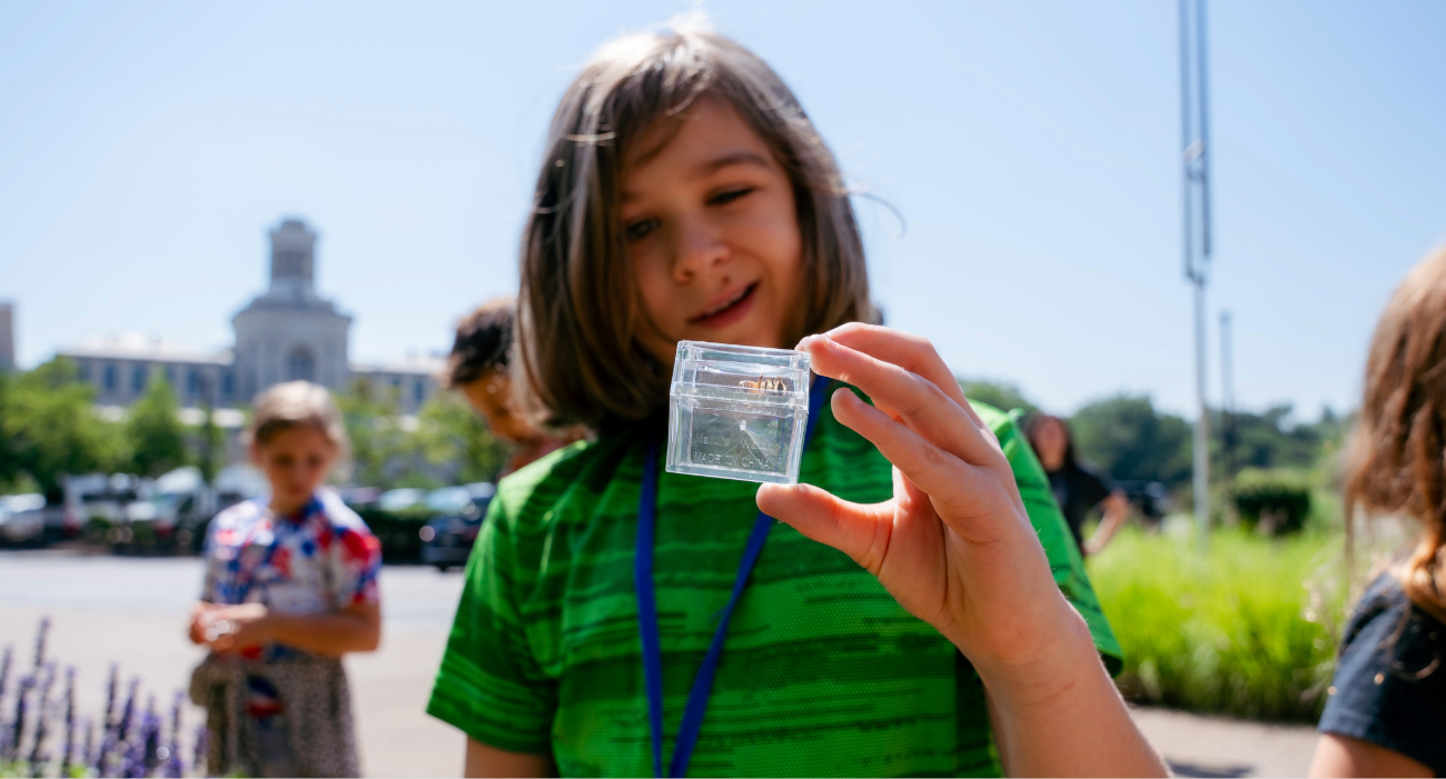 child posing with bug in a clear box