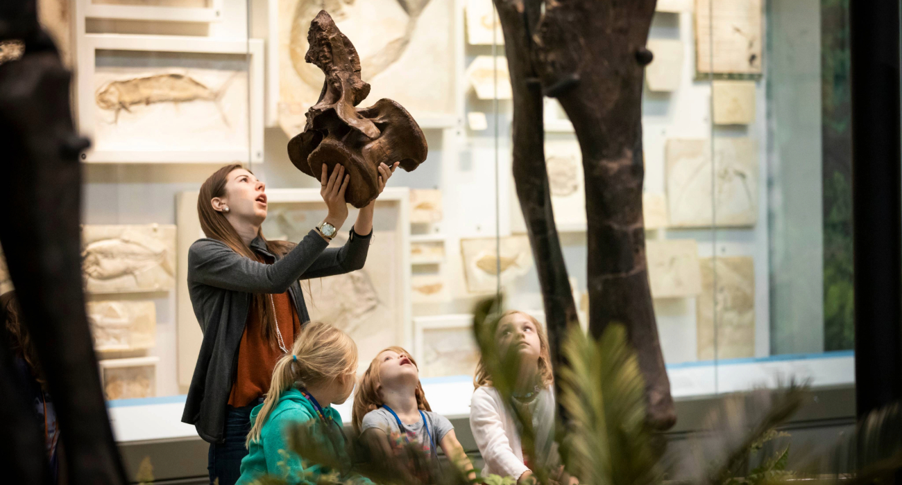 teacher holding dinosaur pelvis in front of children